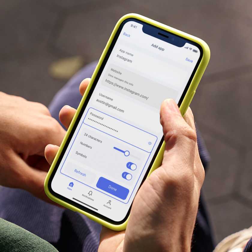 Image of hand holding phone with yellow cover that’s displaying how to generate a password in Okta Personal