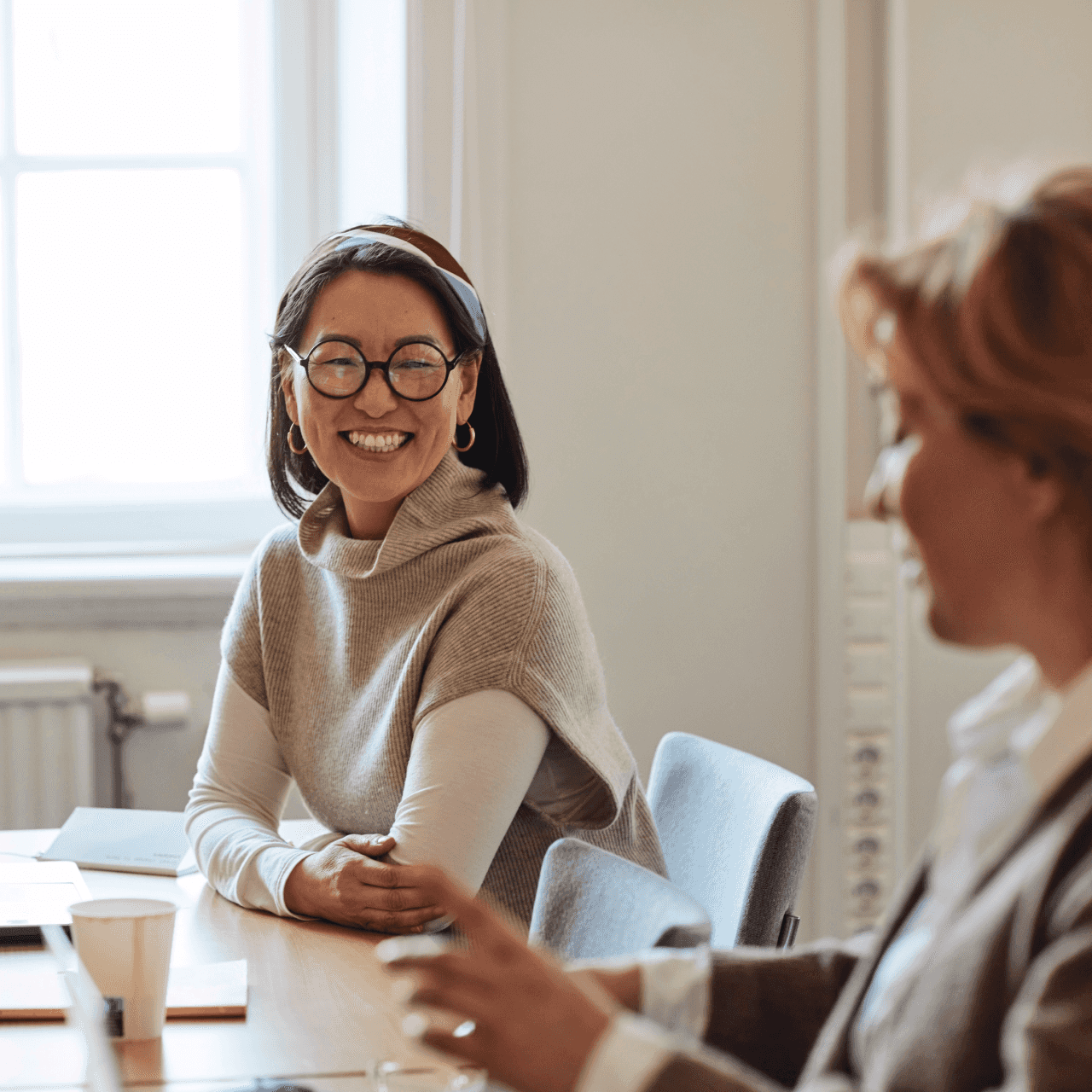 Image of a woman smiling to another one in an office.