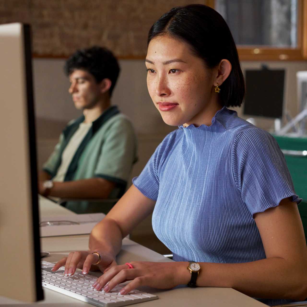 A woman working on her computer next to a coworker.