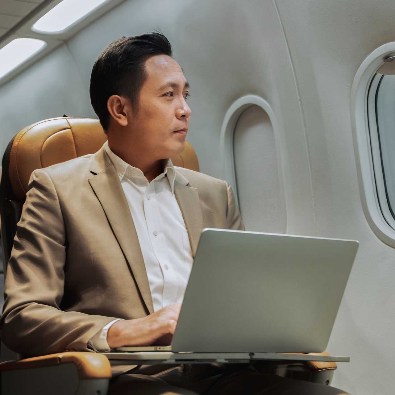 Man sitting on train with laptop out looking out the window