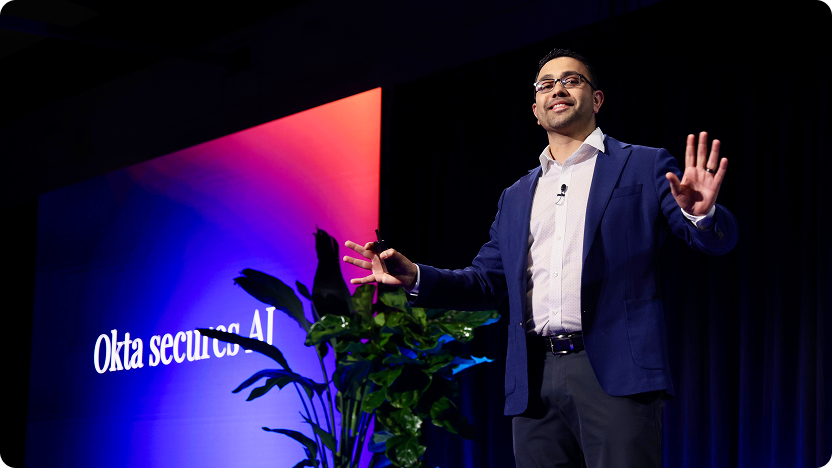 Harish Peri in a blue suit jacket standing on stage with arms outstretched.