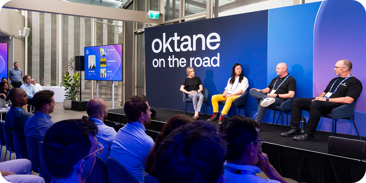 Four panelists seated on a stage in front of a blue backdrop with the text "Oktane on the road" speaking to an audience.