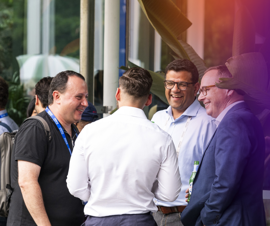Four professionals standing in a circle, smiling and conversing during a networking session at a tech event.