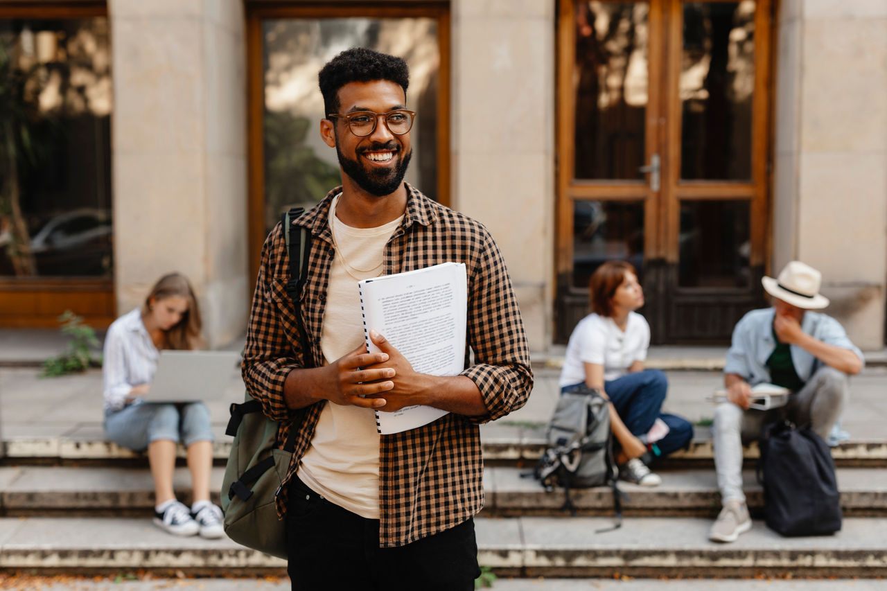 African male student walking out from university.
