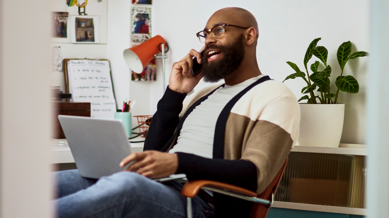 Man on phone holding laptop