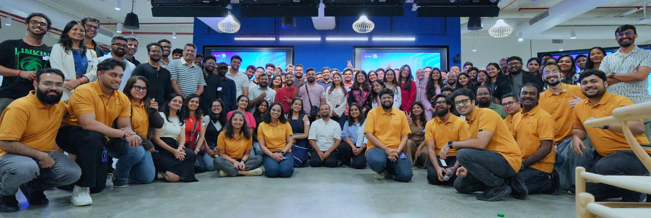 A large group of colleagues poses together for a team photo in a modern office space. 