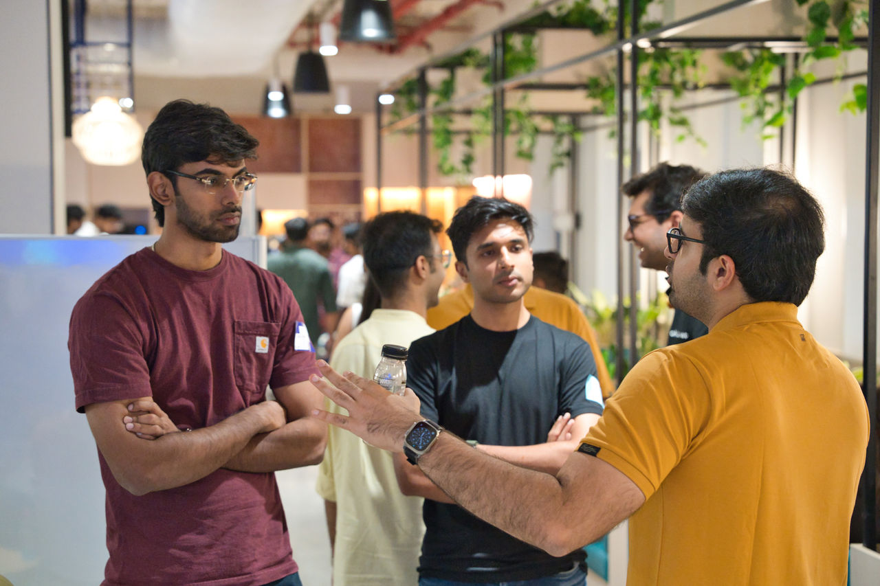 A group of young adults stand together having a discussion in a modern office space. 