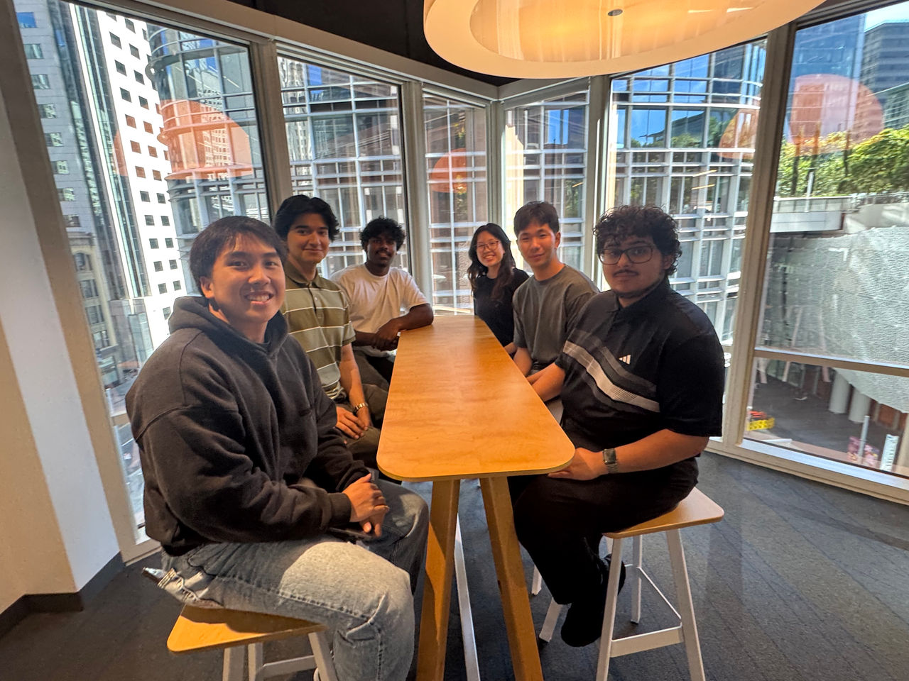 A group of individuals seated around a wooden table in a contemporary office setting. 