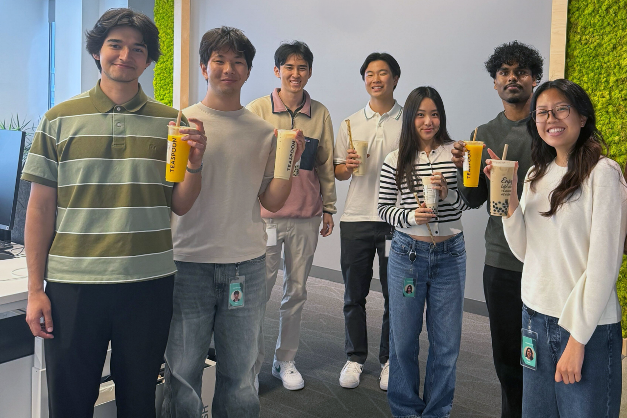 A group of individuals holding various bubble tea drinks in a modern office environment. 