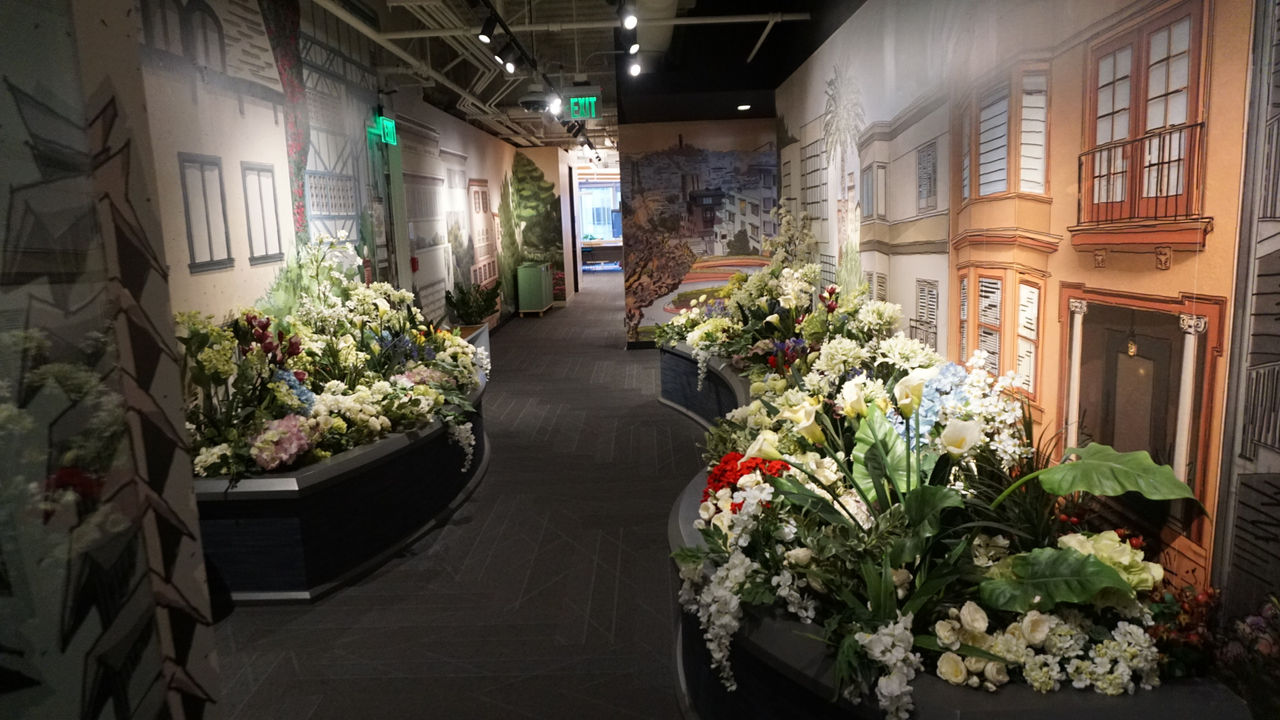 A vibrant indoor floral arrangement set within an urban-themed environment featuring building facades and street visuals.