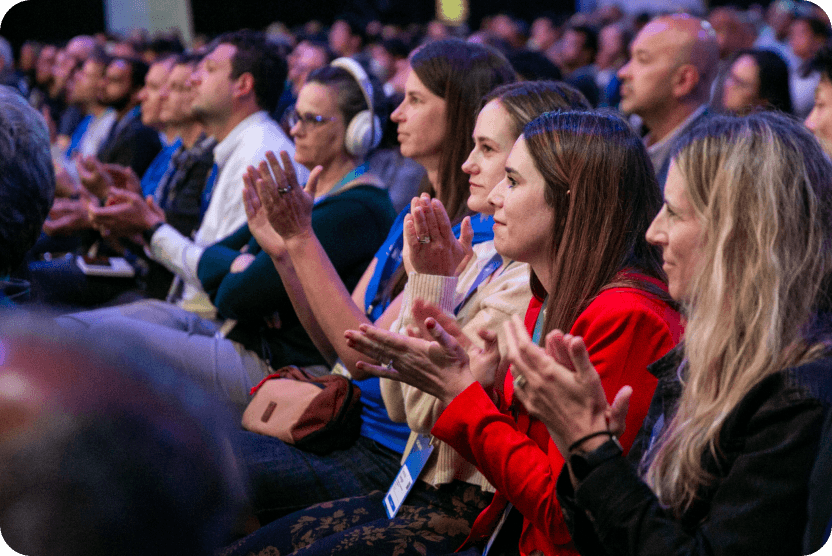 An image focused on a group of attendees sitting and clapping at an Okta conference.