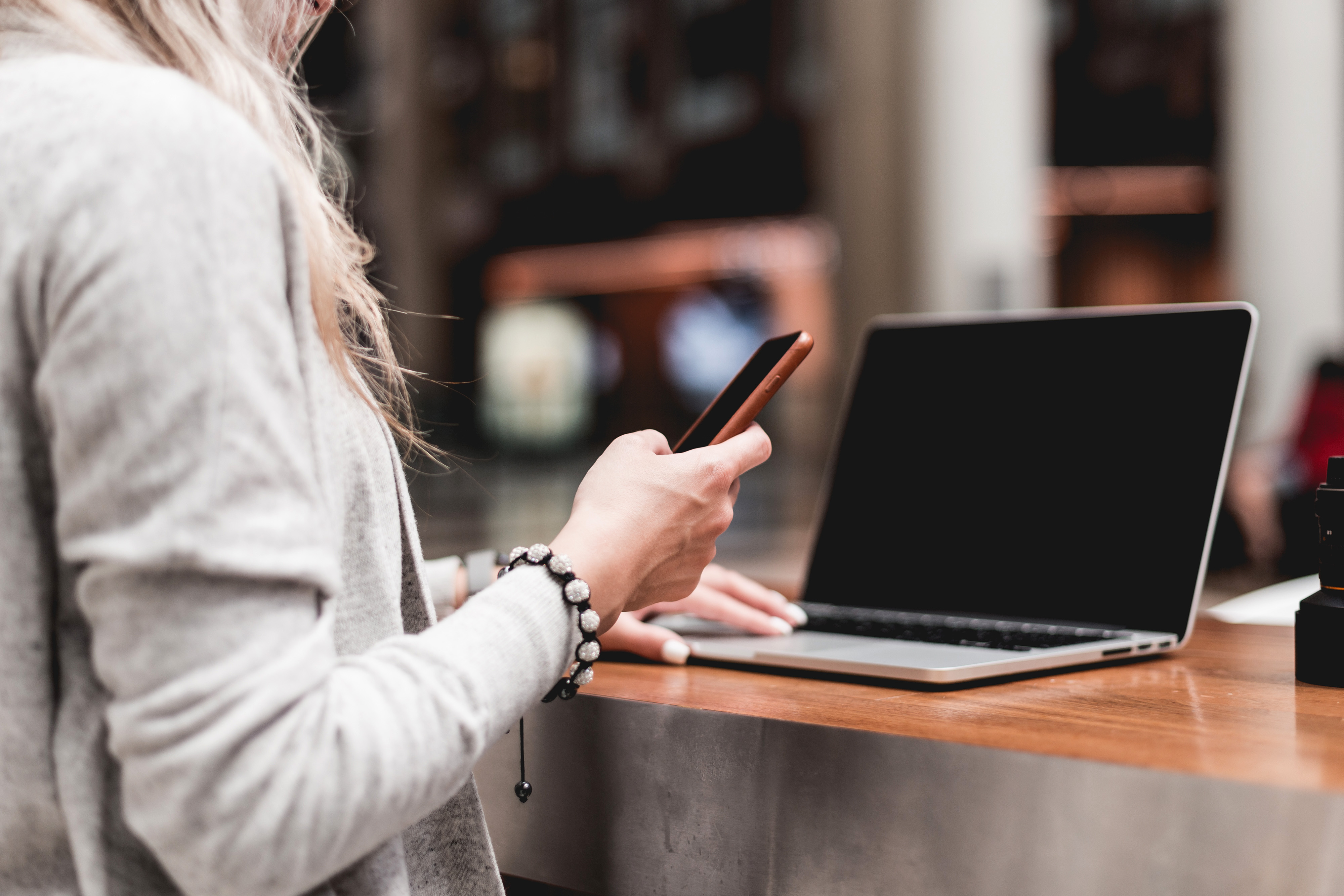 woman using her smartphone while working remotely on laptop picjumbo com