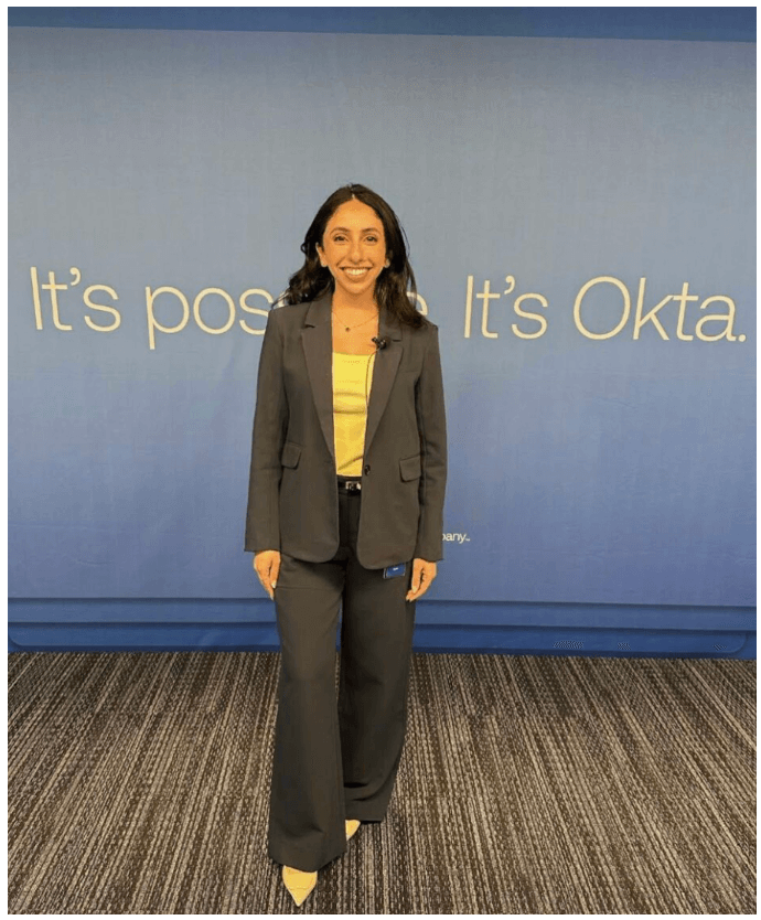 Sophia Jadallah standing and smiling in front of Okta catch phrase
